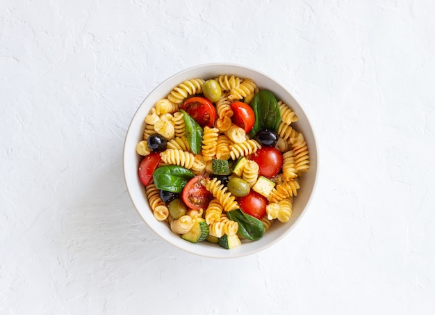 Nudelsalat mit Tomaten, Zucchini, Oliven und Spinat. Gesundes Essen. Vegetarisches Essen.