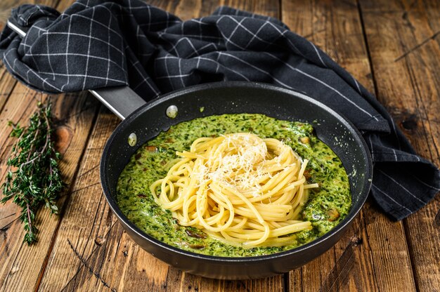 Nudelspaghetti mit Pesto-Sauce und frischem Spinat und Parmesan in einer Pfanne