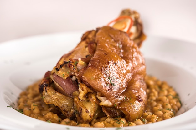 Nudillo de cerdo con frijoles, plato blanco, fondo claro, aislado