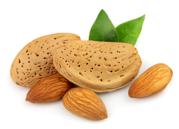 Nueces de almendra con hojas de cerca en blanco