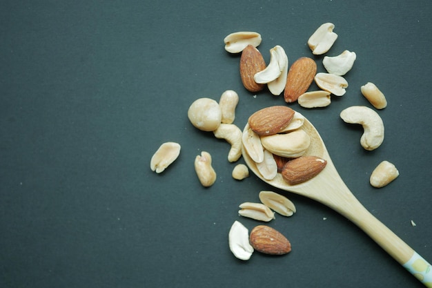 Nueces de almendras en una cuchara de madera sobre fondo negro