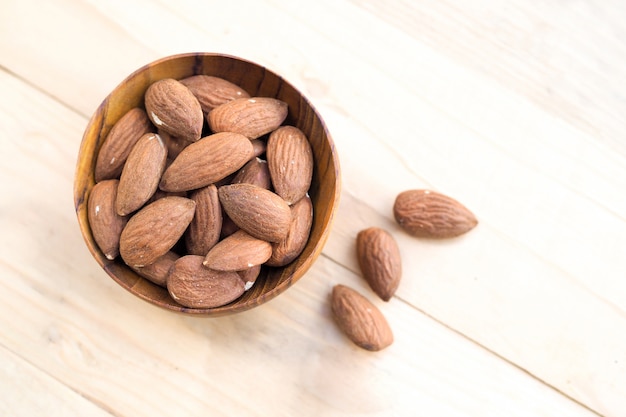 Nueces almendras en cuencos de madera sobre fondo de mesa de madera