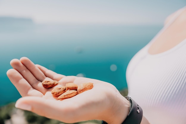 Nueces de almendras lechosas jóvenes en la mano de una mujer una joven mujer caucásica comiendo almendras frescas después de la mañana