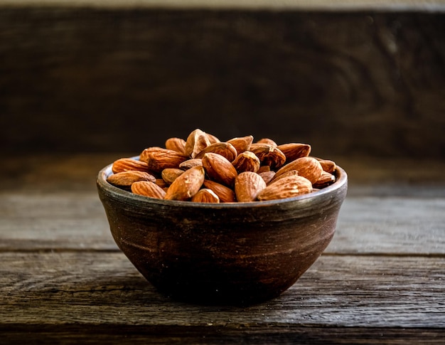 Nueces de almendras en loza sobre un fondo de madera.