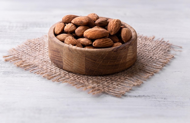 Nueces de almendras en la placa de madera marrón en el catálogo de fondo de madera blanca