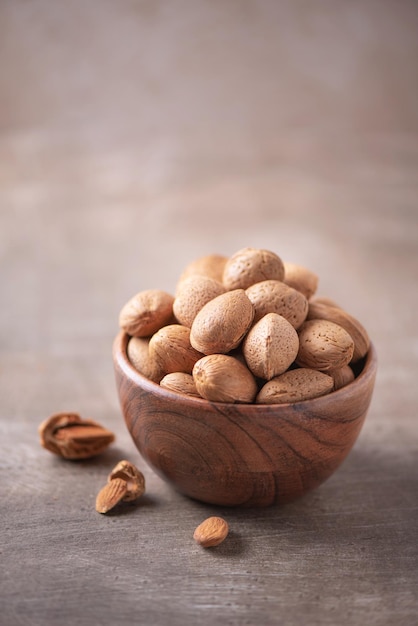 Nueces de almendras en un tazón de madera sobre fondo con textura de madera Espacio de copia Superalimento concepto de comida vegetariana vegana Macro de textura de nuez de almendras enfoque selectivo Tentempié saludable