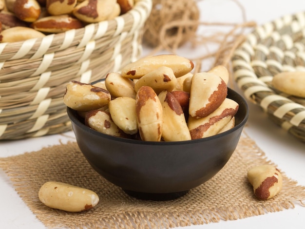 Nueces de Brasil servidas en un recipiente aislado en la vista lateral de la servilleta de nueces sobre fondo gris