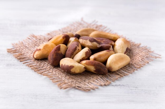 nueces de Brasil en el trozo de arpillera en la mesa de madera blanca. catalogar.