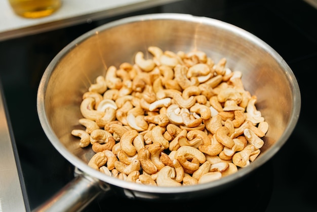 Foto nueces de caju asadas en una sartén en una estufa eléctrica cocinar nueces dulces nutritivas deliciosas