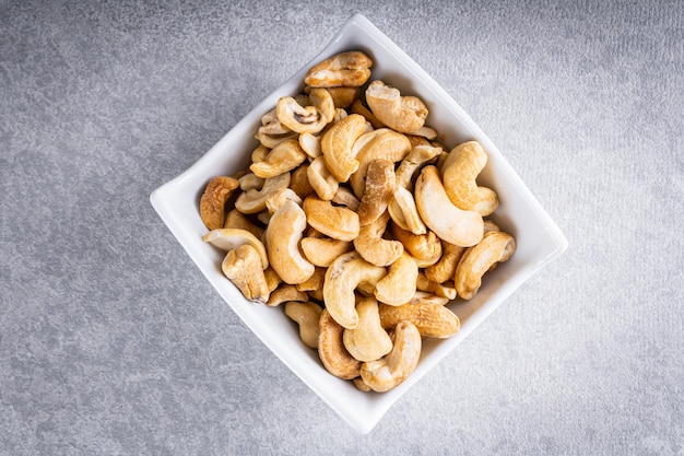 Nueces de cajú en una olla de vajilla sobre fondo blanco de madera