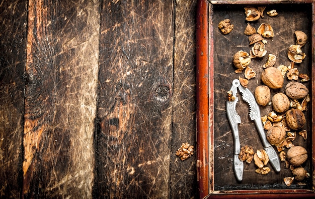 Nueces con cascanueces sobre mesa de madera.