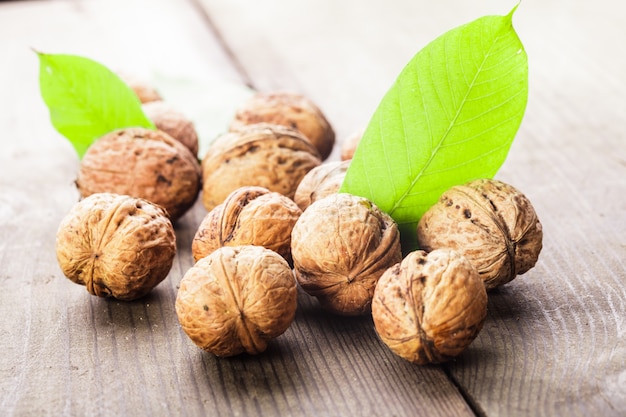 Nueces con cáscara y hoja verde sobre la mesa de madera