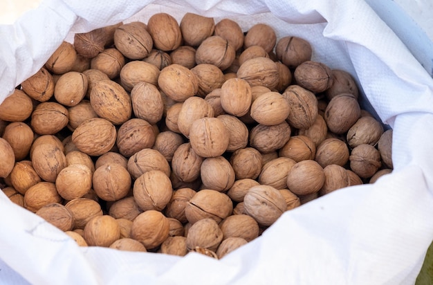 Nueces con cáscara en una vista superior de bolsa blanca.