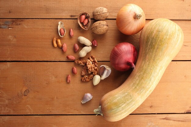 Nueces, cebolla, ajo y calabaza sobre un fondo de madera Nueces y verduras en una mesa de madera closeup Concepto de comida vegana