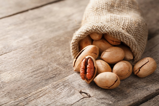 Las nueces se derraman de una tela de saco sobre una mesa de madera