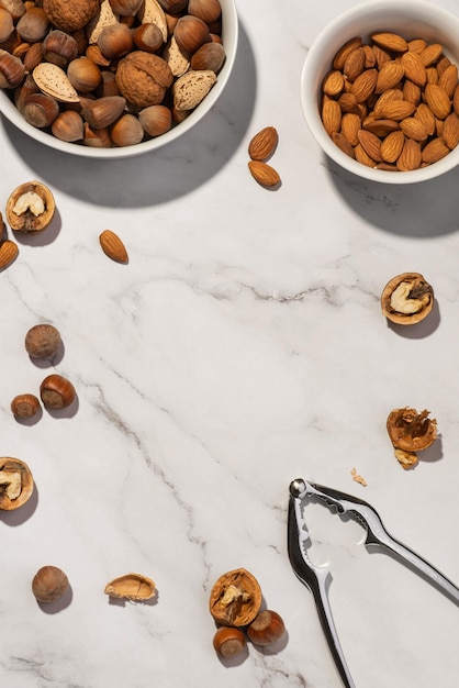 Nueces diferentes en un plato blanco con un cascanueces en una mesa gris