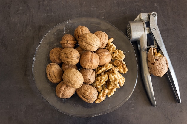 Las nueces se encuentran en un plato de vidrio junto con un Cascanueces. Comida sana.