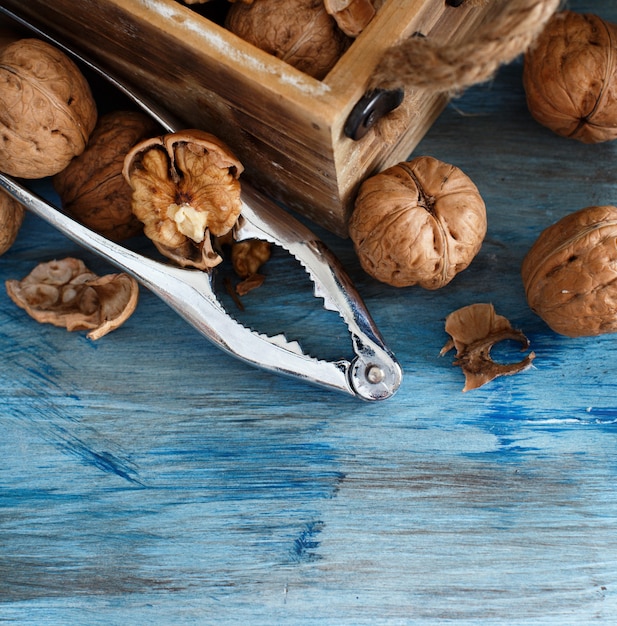 Nueces frescas con un cascanueces sobre una mesa de madera azul