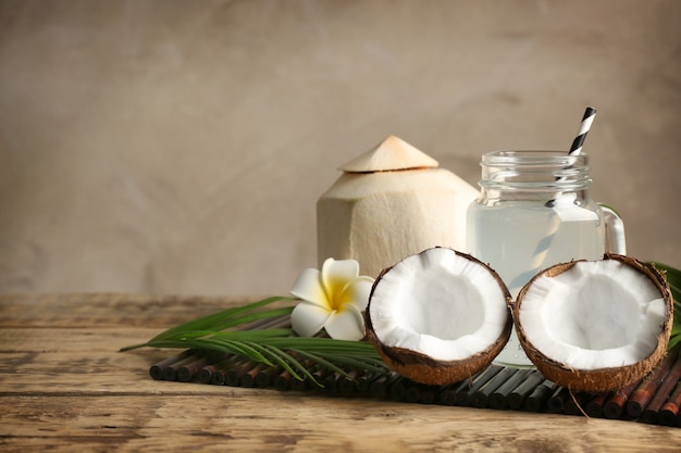 Nueces frescas y tarro de masón con agua de coco en estera de bambú