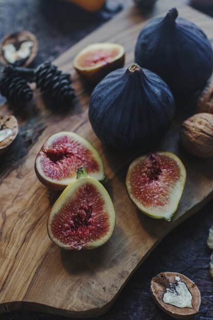 Nueces de higos orgánicos frescos y hojas de otoño sobre tablero de madera y mesa de piedra oscura