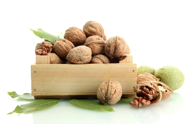 Nueces con hojas verdes en caja de madera aisladas en blanco