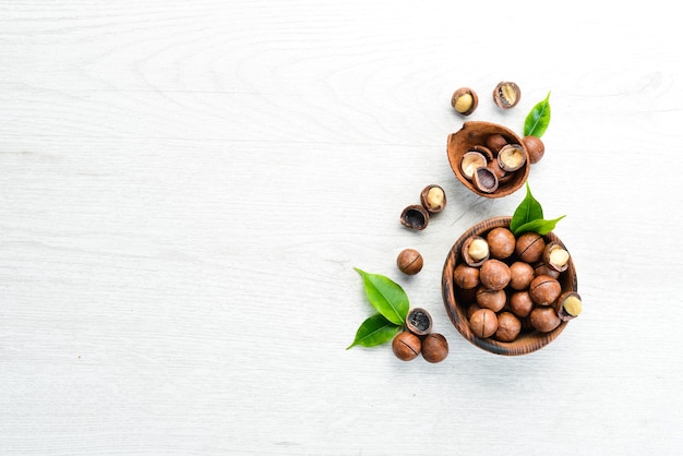 Nueces de macadamia en un cuenco sobre un fondo de madera blanca