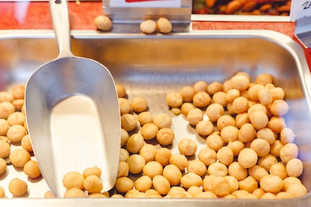 Nueces de macadamia orgánicas crudas frescas para la venta en el mercado de agricultores en el escaparate de la tienda con una primicia en el mercado de agricultores. Comida vegana, nutrición saludable, concepto de comida cetogénica, nueces de macadamia.