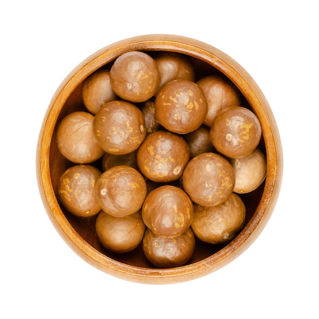 Nueces de macadamia en sus cáscaras en un cuenco de madera