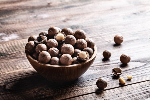 Nueces de macadamia en un tazón en la vieja mesa rústica de madera