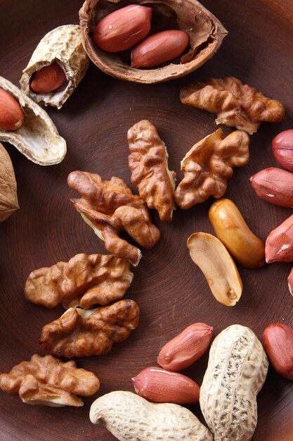 Nueces y maní en un plato de arcilla Comida vegana Nueces peladas y sin cáscara en un tazón de arcilla marrón primer plano