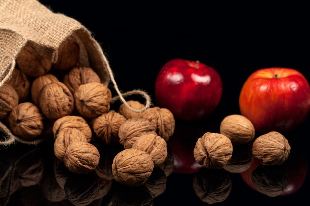 Nueces y manzanas enteras en una tabla en un fondo negro