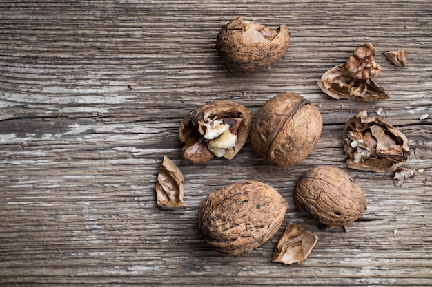 Nueces en una mesa rústica envejecida de madera. Nueces rotas y trituradas