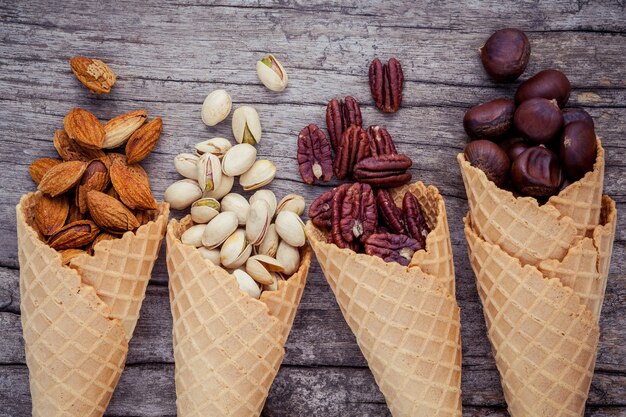 Nueces mezcladas en conos de la galleta en el fondo de madera lamentable para el diseño del menú de los dulces.