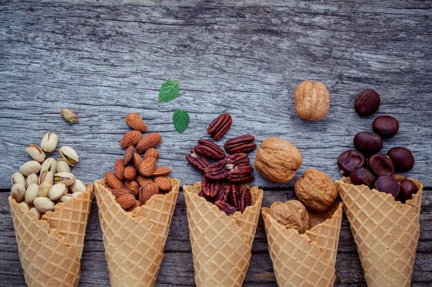 Nueces mezcladas en conos de la galleta en fondo de madera lamentable.