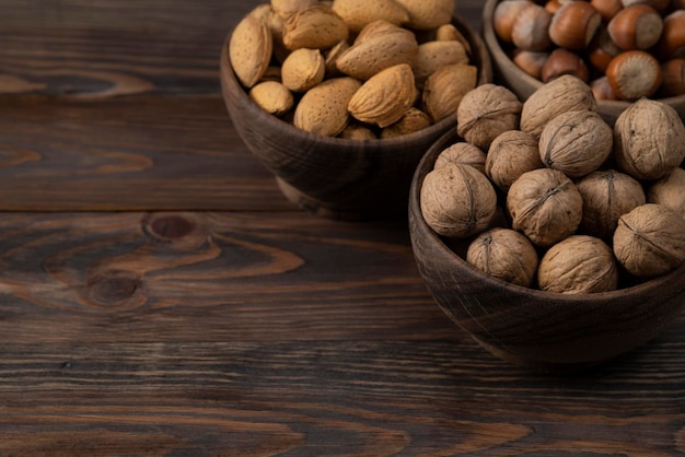 Nueces mixtas en recipiente de madera sobre fondo de madera