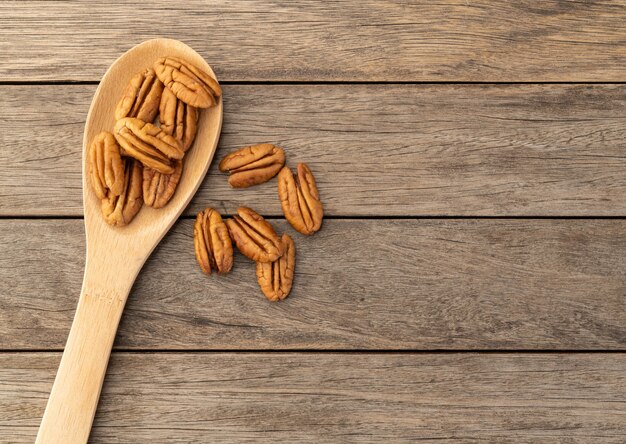 Nueces de pacana en una cuchara sobre la mesa de madera con espacio de copia.