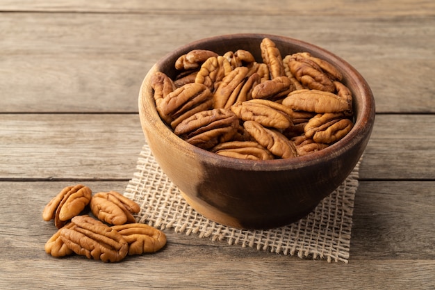 Nueces de pacana en un recipiente sobre la mesa de madera.