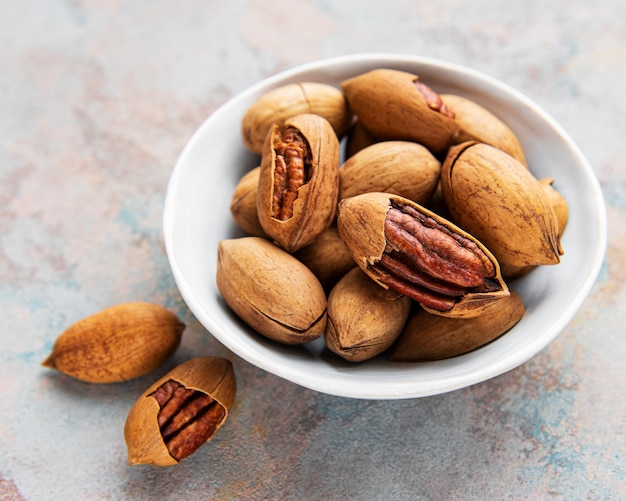 Nueces de pacana en un recipiente sobre una superficie de hormigón gris