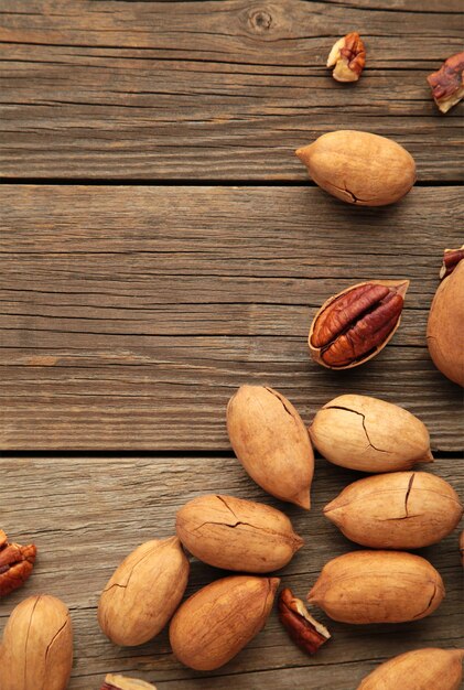 Nueces de pacana sobre una mesa de madera marrón. foto vertical.