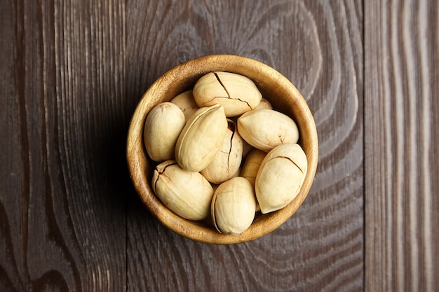 Nueces de pacana en un tazón en la vista superior de la mesa de madera marrón