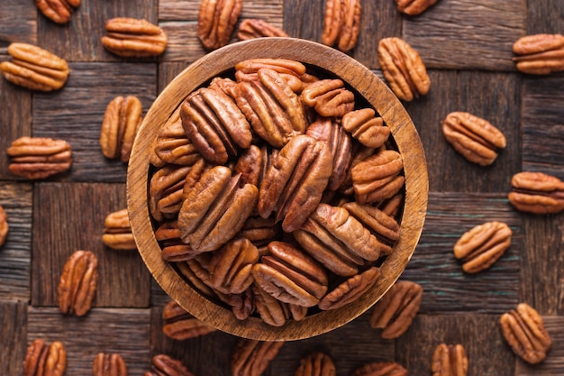 Nueces pecanas peladas en un recipiente sobre la mesa de madera.