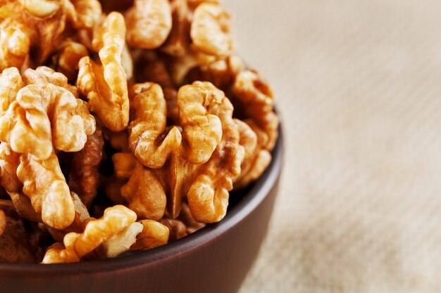 Nueces peladas en una taza de madera de color marrón oscuro sobre un paño de arpillera.