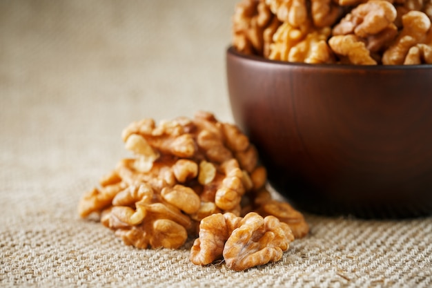 Nueces peladas en una taza de madera de color marrón oscuro sobre un paño de arpillera