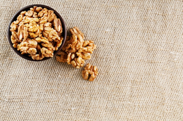 Nueces peladas en una taza de madera de color marrón oscuro sobre un paño de arpillera