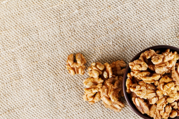 Nueces peladas en una taza de madera de color marrón oscuro sobre un paño de arpillera