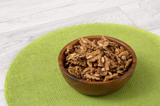 Nueces peladas en una taza de madera sobre una servilleta verde