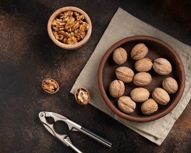 Nueces sin pelar, cascanueces y granos pelados en una pared marrón. alimentación saludable