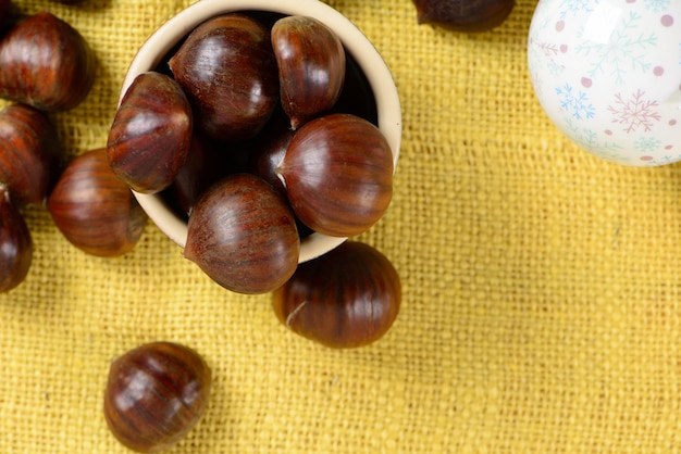 Nueces portuguesas en recipiente de cerámica en mesa con yute amarillo