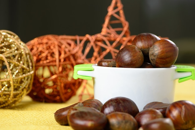 Nueces portuguesas en recipiente de cerámica sobre yute amarillo y con adornos navideños