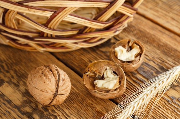 Nueces de primer plano, espiga de trigo y cesta de mimbre sobre tablas de madera antiguas. Poca profundidad de campo. Vista superior.